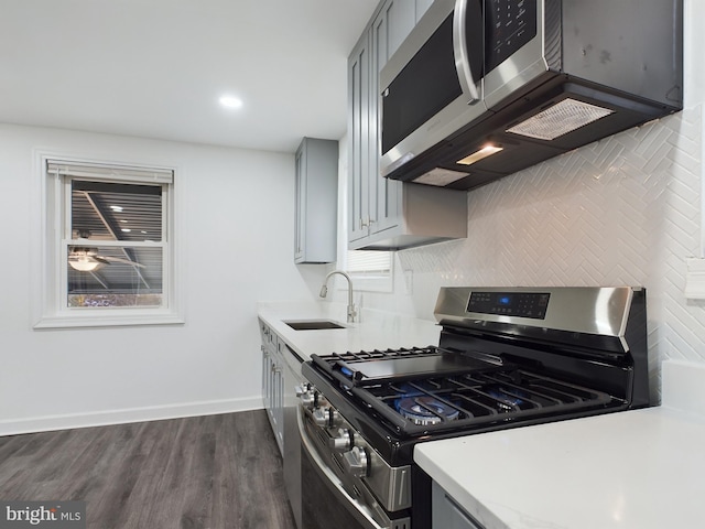 kitchen featuring tasteful backsplash, sink, gray cabinetry, stainless steel appliances, and dark wood-type flooring