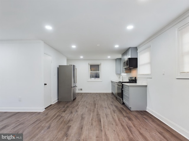 kitchen with stainless steel appliances, hardwood / wood-style floors, and gray cabinetry