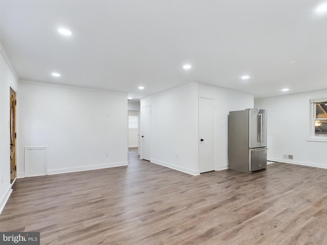 interior space featuring ornamental molding, stainless steel refrigerator, and light wood-type flooring