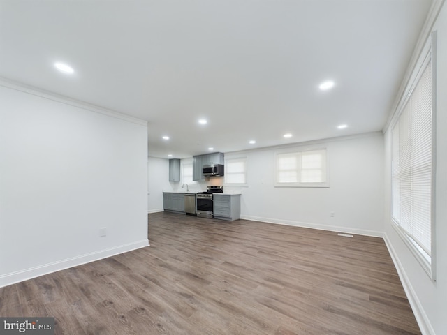 unfurnished living room with crown molding, sink, and hardwood / wood-style floors