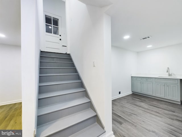 staircase with sink and wood-type flooring