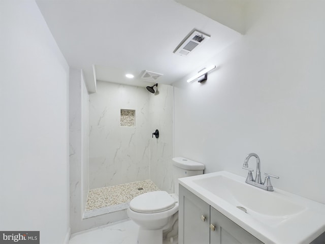 bathroom with tiled shower, vanity, and toilet