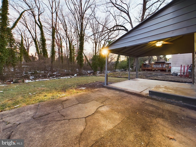 patio terrace at dusk featuring a gazebo, a deck, ceiling fan, and a lawn