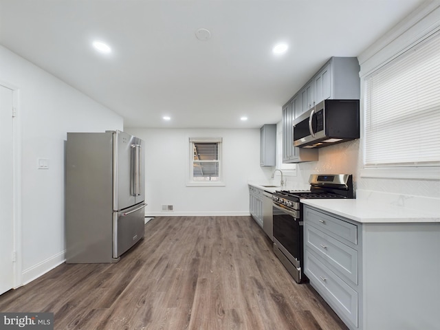 kitchen with appliances with stainless steel finishes, dark hardwood / wood-style flooring, sink, and gray cabinetry