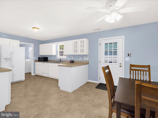 kitchen with glass insert cabinets, stainless steel microwave, a peninsula, white fridge with ice dispenser, and a sink