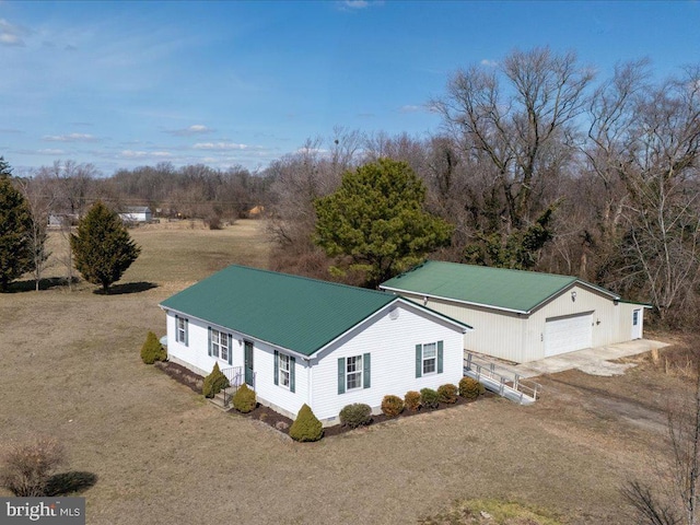 exterior space with an outbuilding, metal roof, an attached garage, dirt driveway, and crawl space