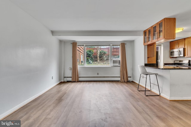 kitchen featuring a baseboard heating unit, light wood-type flooring, dark stone counters, and stainless steel appliances