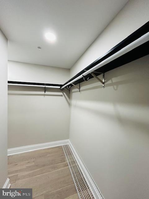 walk in closet with wood finished floors