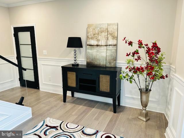 details with a wood stove, crown molding, a decorative wall, and wood finished floors