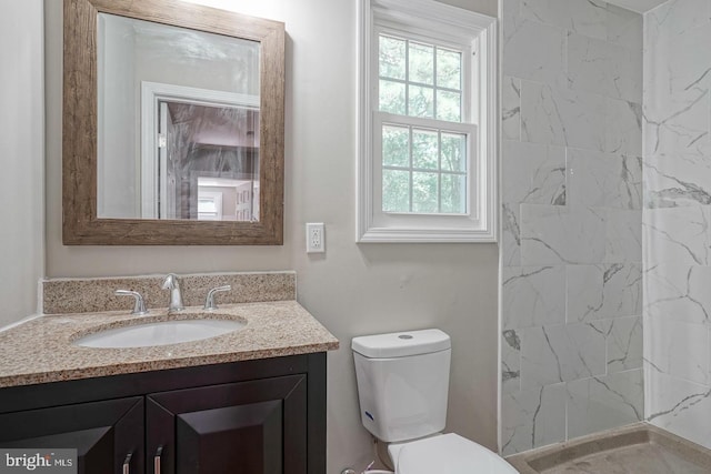 bathroom featuring vanity, toilet, and a tile shower