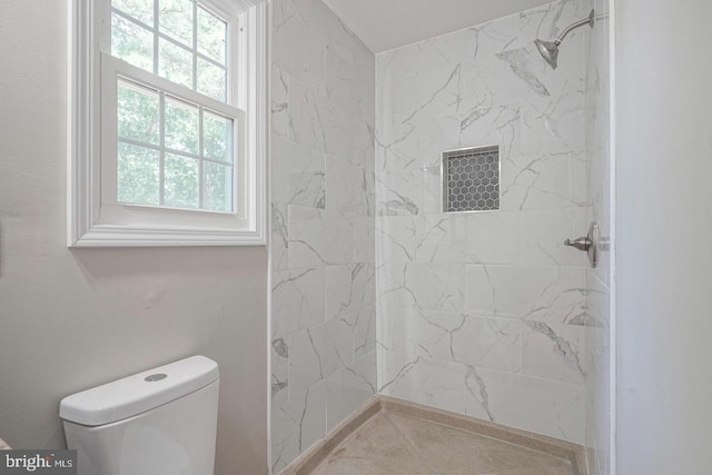 bathroom featuring a tile shower and toilet