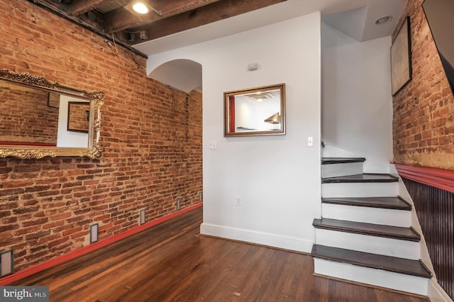 stairs featuring brick wall and hardwood / wood-style floors