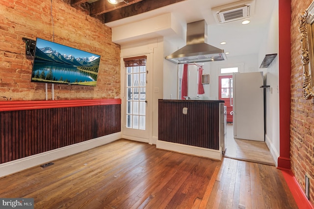 kitchen featuring brick wall, hardwood / wood-style floors, white refrigerator, island exhaust hood, and beam ceiling