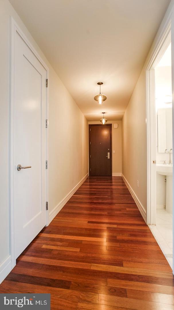 hall featuring dark wood-style flooring and baseboards