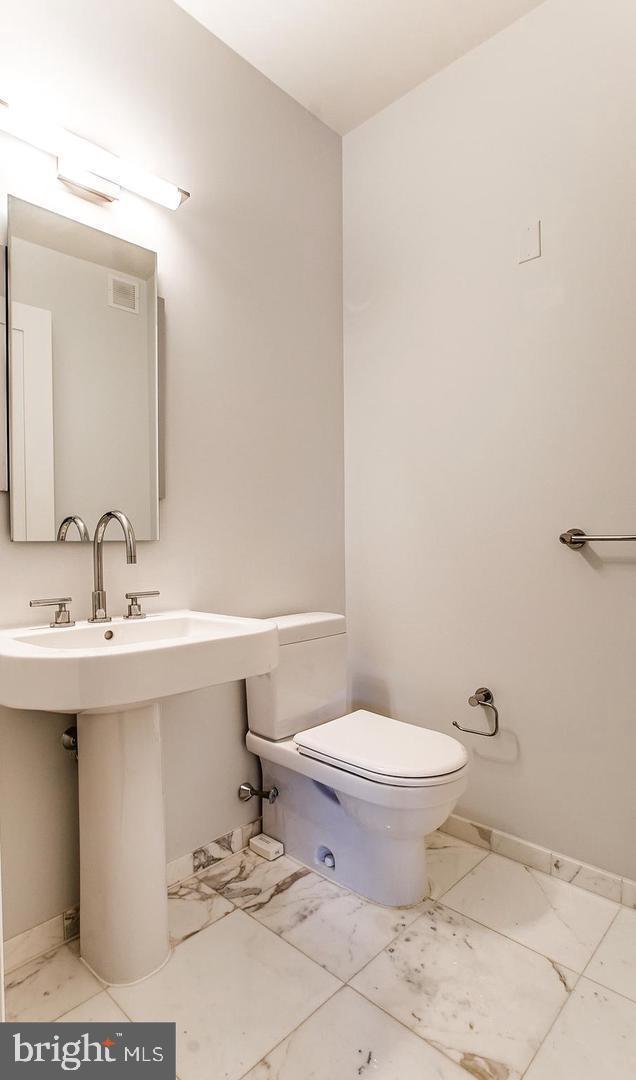 bathroom featuring baseboards, visible vents, toilet, marble finish floor, and a sink