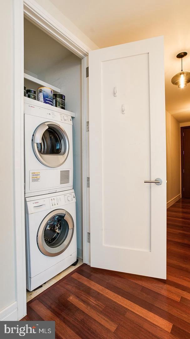 laundry room with stacked washer and dryer, laundry area, and wood finished floors