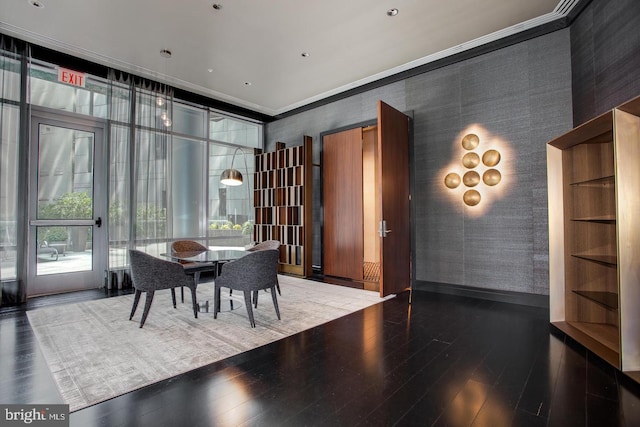 dining space featuring ornamental molding, dark wood-style flooring, wallpapered walls, and a wall of windows