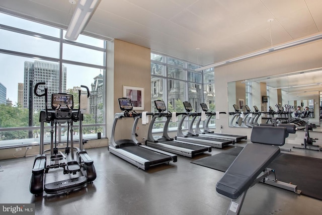 gym with a healthy amount of sunlight, a view of city, and floor to ceiling windows