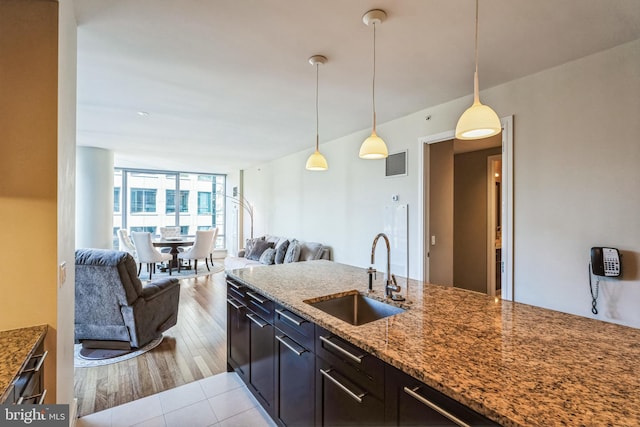 kitchen with visible vents, dark stone counters, open floor plan, decorative light fixtures, and a sink