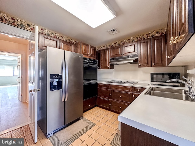 kitchen with sink, light tile patterned floors, dark brown cabinets, and stainless steel appliances