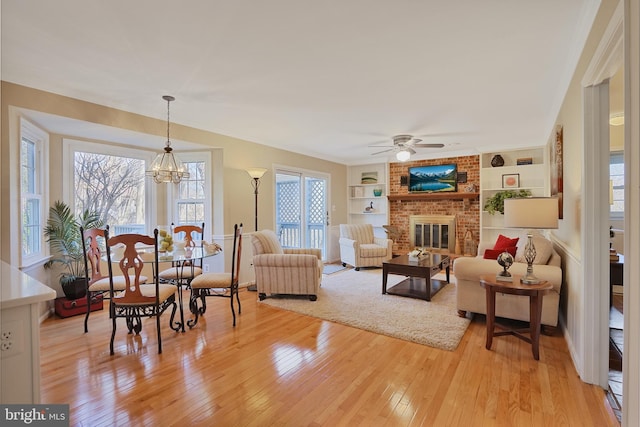 living room with light wood-style floors, a wealth of natural light, a fireplace, and built in shelves