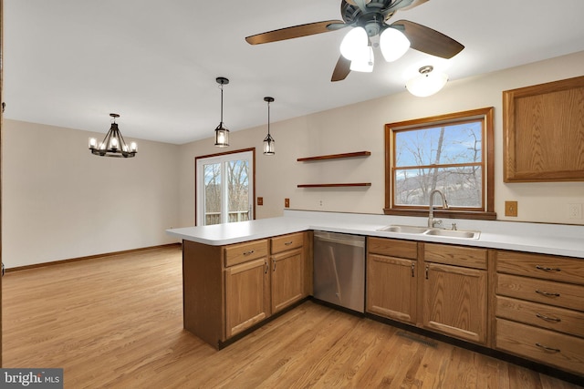 kitchen featuring a peninsula, a sink, stainless steel dishwasher, and decorative light fixtures