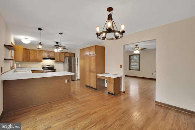 kitchen featuring a peninsula, a sink, light countertops, appliances with stainless steel finishes, and brown cabinets