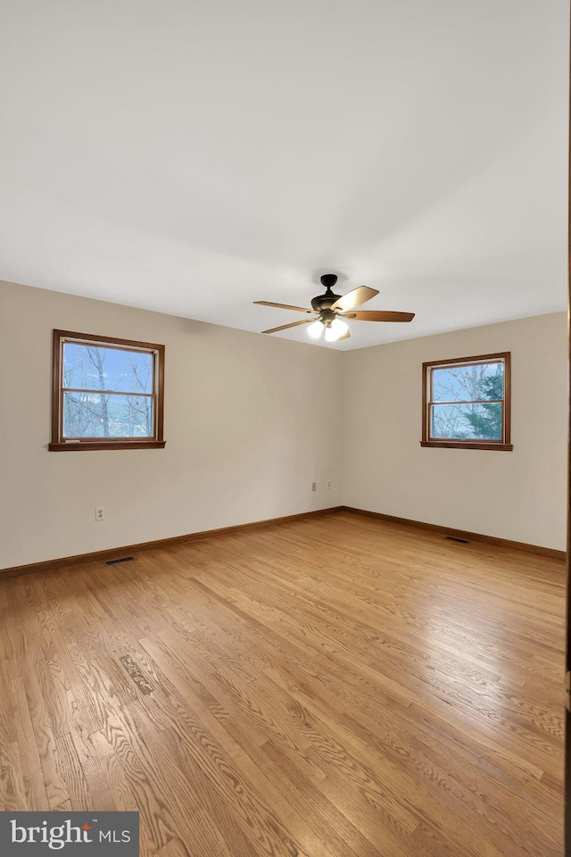 unfurnished room with light wood finished floors, a ceiling fan, baseboards, and a wealth of natural light