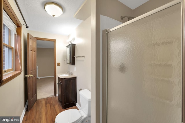 full bathroom featuring baseboards, toilet, wood finished floors, vanity, and a shower stall