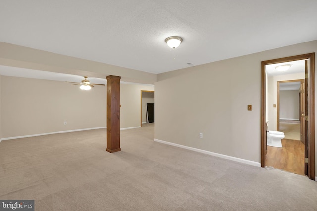 below grade area with light carpet, ceiling fan, a textured ceiling, and baseboards