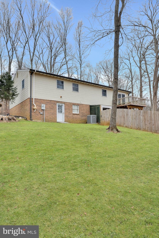 back of house with cooling unit, brick siding, a lawn, and fence