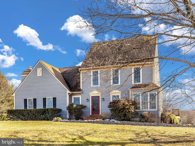 colonial home featuring a front lawn, a chimney, and a shingled roof