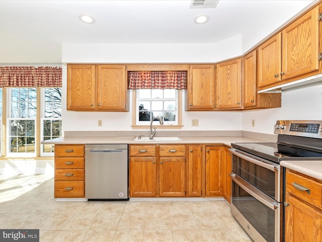 kitchen featuring appliances with stainless steel finishes, a healthy amount of sunlight, light countertops, and a sink