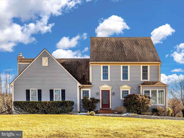 view of front of house with entry steps, a shingled roof, a chimney, and a front lawn