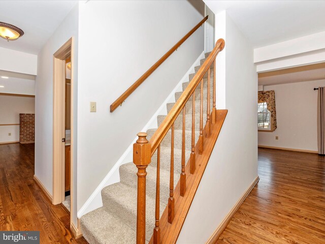 staircase featuring wood finished floors and baseboards