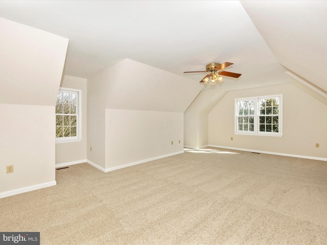 bonus room featuring lofted ceiling, baseboards, a ceiling fan, and light colored carpet