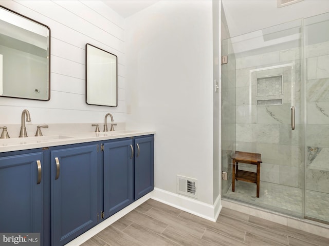 full bathroom featuring double vanity, visible vents, a sink, and wood finish floors