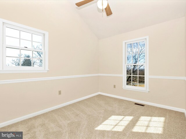 carpeted empty room with vaulted ceiling, visible vents, plenty of natural light, and baseboards