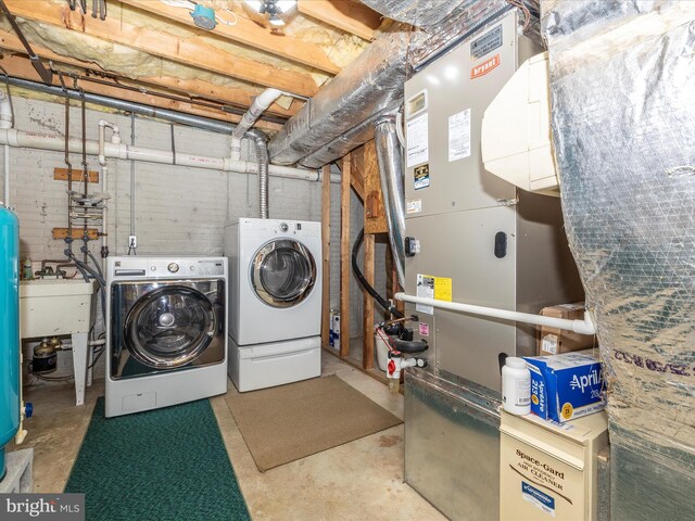 laundry area with a sink, laundry area, washing machine and clothes dryer, and heating unit