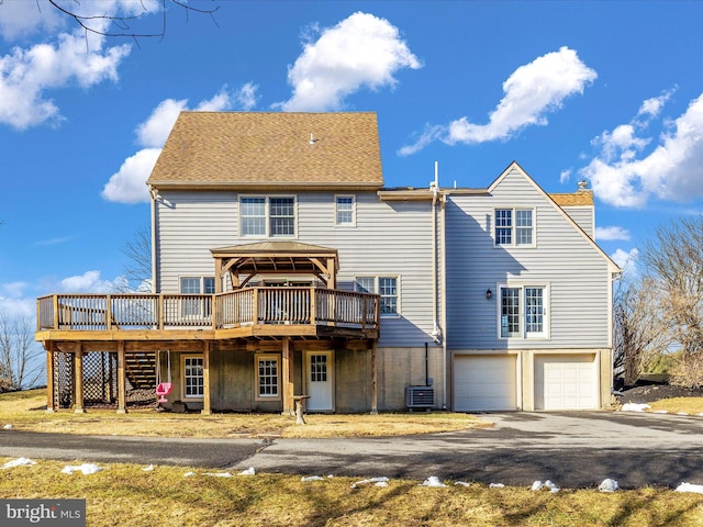 rear view of house featuring a deck, a garage, central AC, driveway, and a chimney