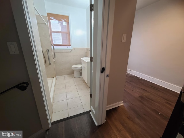 bathroom with a shower, wood-type flooring, tile walls, and toilet