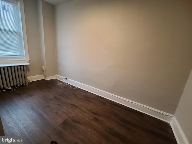 spare room with radiator heating unit and dark hardwood / wood-style floors