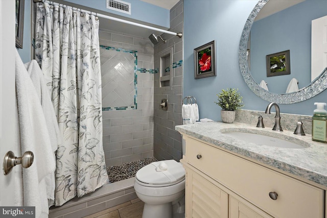 bathroom with visible vents, a shower stall, toilet, and vanity