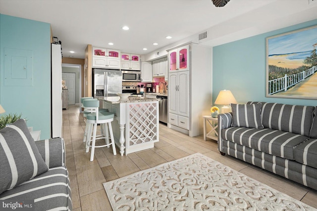 living area featuring light wood finished floors, recessed lighting, visible vents, a barn door, and electric panel