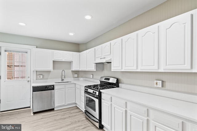 kitchen featuring white cabinetry, sink, light wood-type flooring, and appliances with stainless steel finishes