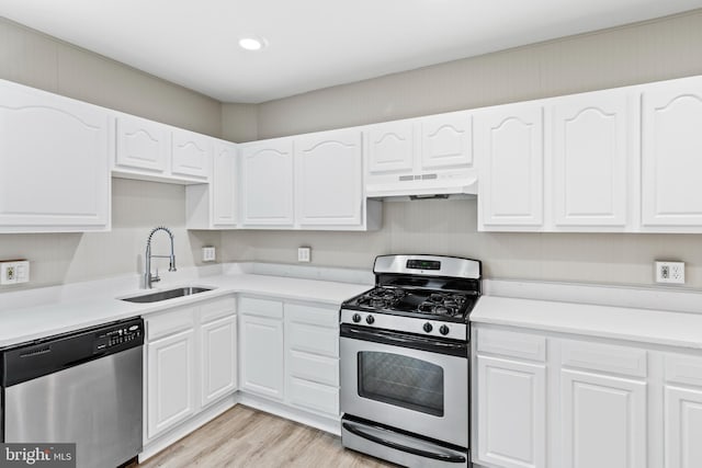 kitchen with white cabinetry, appliances with stainless steel finishes, sink, and light hardwood / wood-style flooring