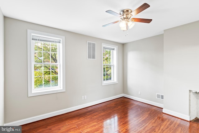 unfurnished room featuring a healthy amount of sunlight, hardwood / wood-style floors, and ceiling fan