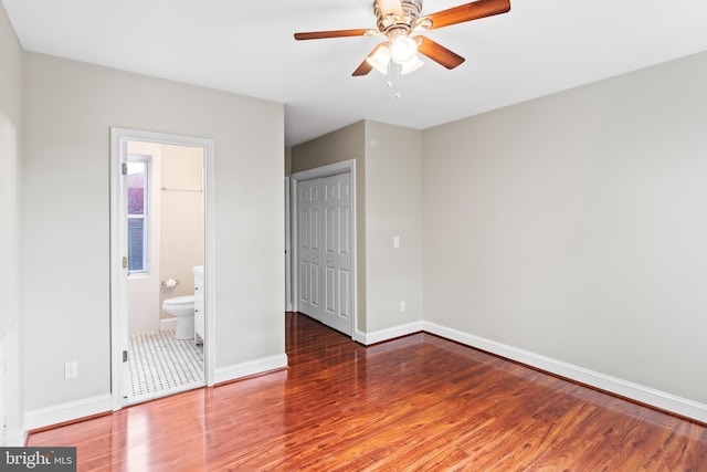 unfurnished bedroom featuring connected bathroom, hardwood / wood-style floors, and a closet