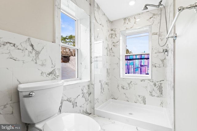 bathroom featuring a healthy amount of sunlight, a tile shower, tile walls, and toilet