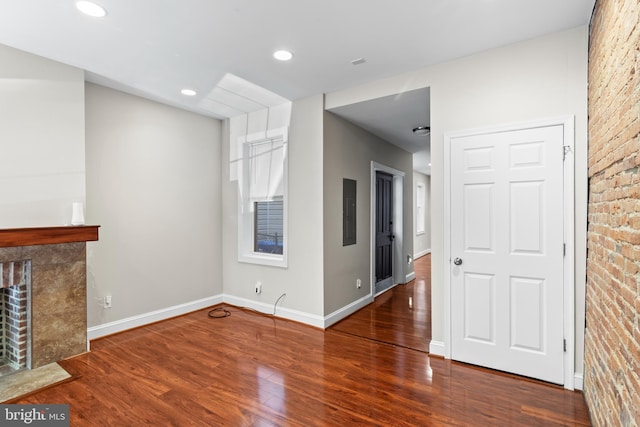 unfurnished living room featuring a fireplace, electric panel, and wood-type flooring